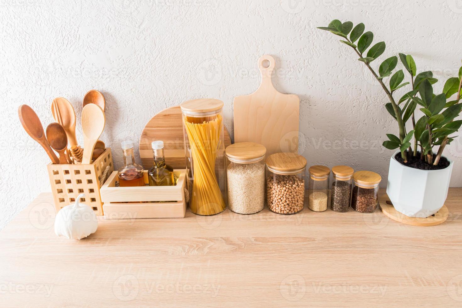 elegante bianca cucina sfondo con cucina utensili su un' di legno controsoffitto contro un' strutturato parete con verde piante d'appartamento. foto