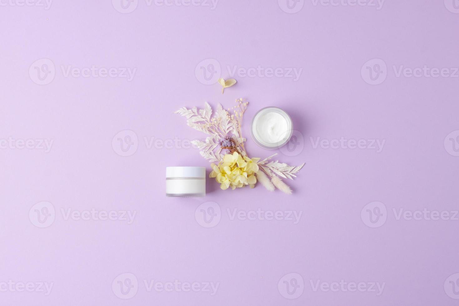 barattoli di cosmetico crema con fiori su rosa sfondo. piatto posizione, copia spazio foto
