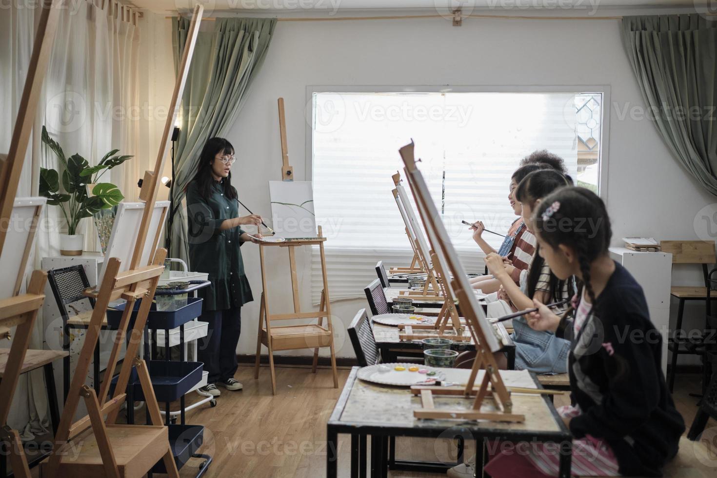 un' femmina asiatico insegnante insegna e dimostra per il bambini su acrilico colore immagine pittura su tela nel arte aula, creativamente apprendimento con abilità a il elementare scuola studio formazione scolastica. foto