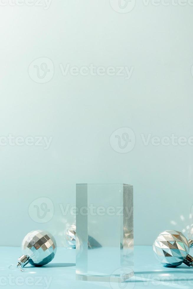 un' minimalista scena di bicchiere podio con Natale decorativo palle su un' leggero blu sfondo foto