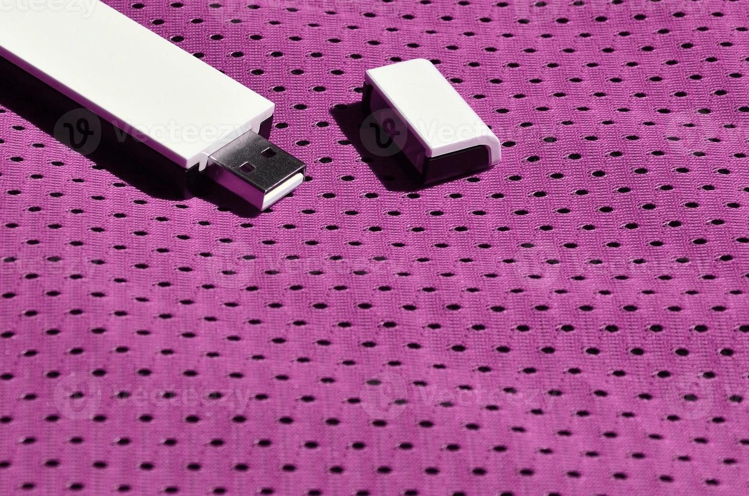 un' moderno portatile USB Wi-Fi adattatore è posto su il viola abbigliamento sportivo fatto di poliestere nylon fibra foto