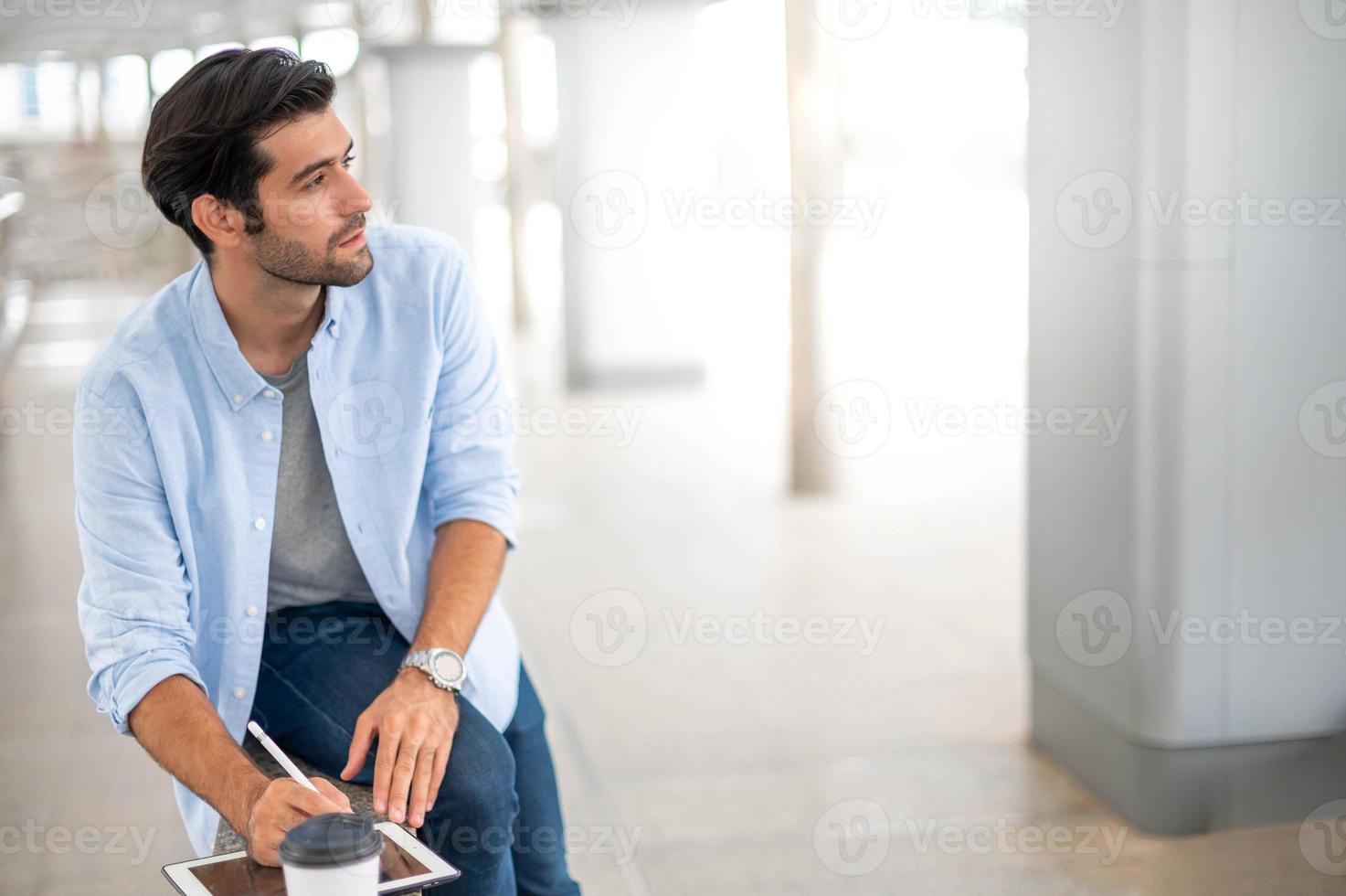 il giovane uomo utilizzando un' tavoletta per Lavorando a su di ufficio. il uomo indossare casuale stoffa e sensazione pensiero e sul serio. foto