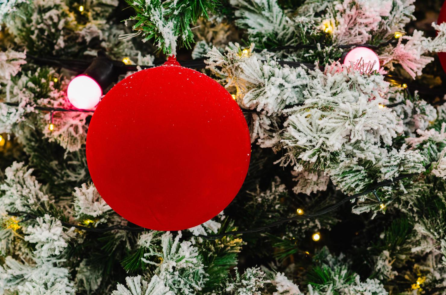 rosso fronzolo e luci decorare su Natale albero quello avere falso neve su esso. foto