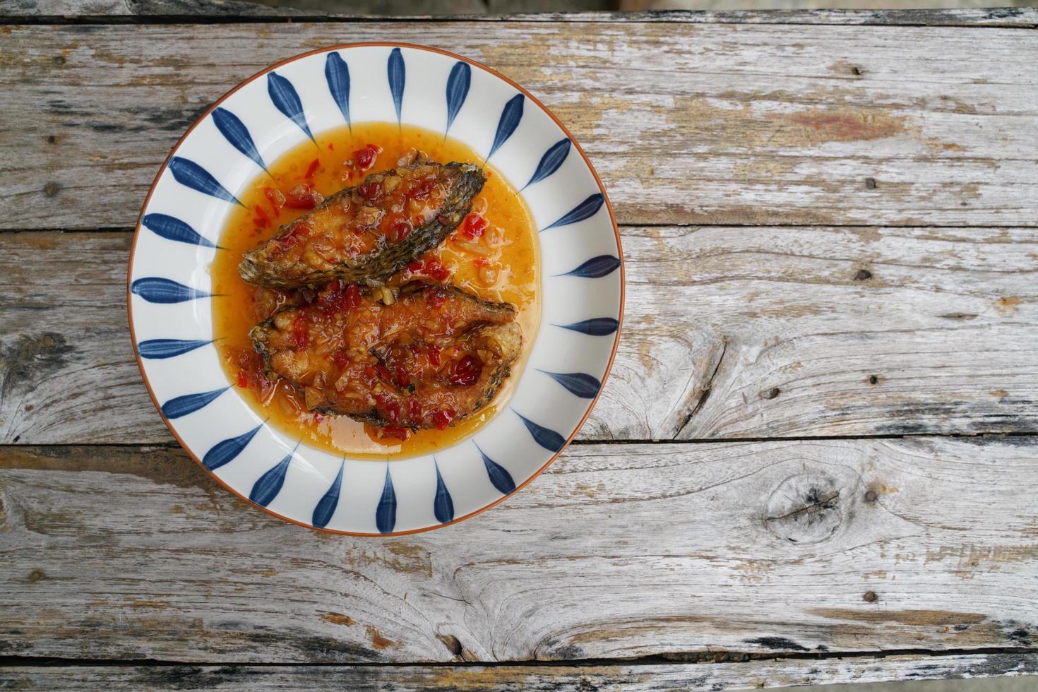 fritte pesce con peperoncino nel un' ceramica piatto su un vecchio di legno pavimento. il gusto è acido, dolce e leggermente speziato. foto