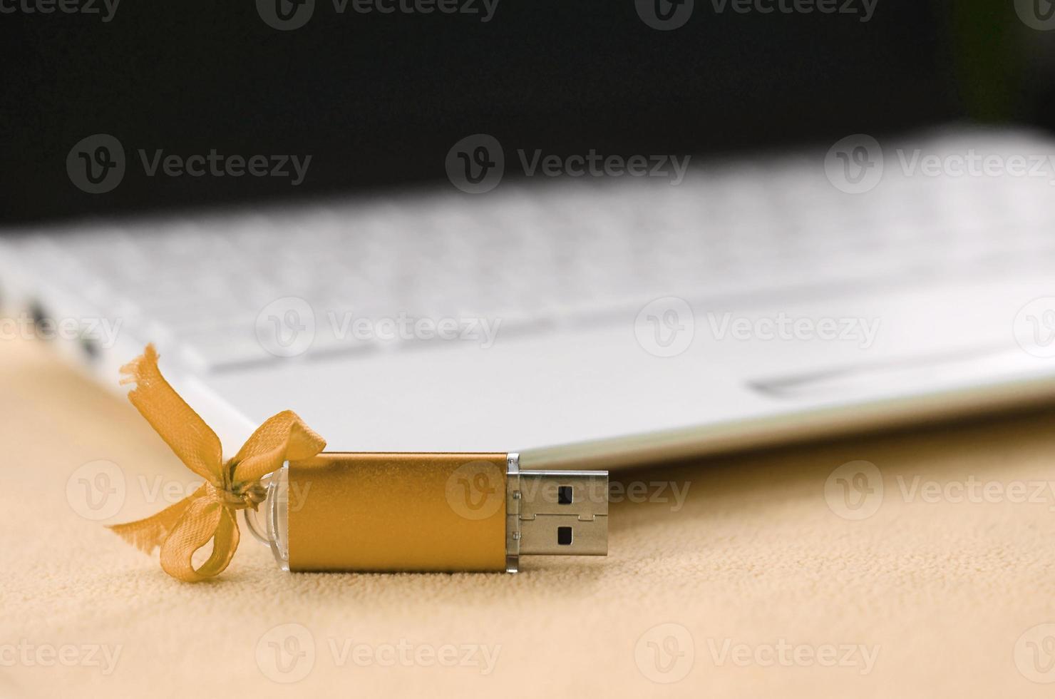 arancia USB veloce memoria carta con un' arco bugie su un' coperta di morbido e peloso arancia vello tessuto accanto per un' bianca il computer portatile. classico femmina regalo design per un' memoria carta foto