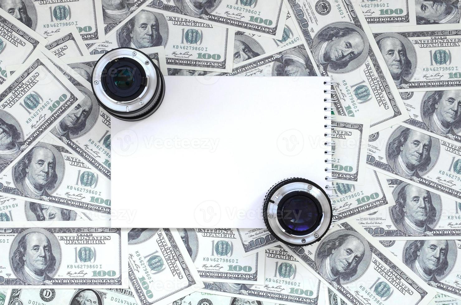 Due fotografico lenti a contatto e bianca taccuino menzogna su il sfondo di un' lotto di dollaro fatture. spazio per testo foto