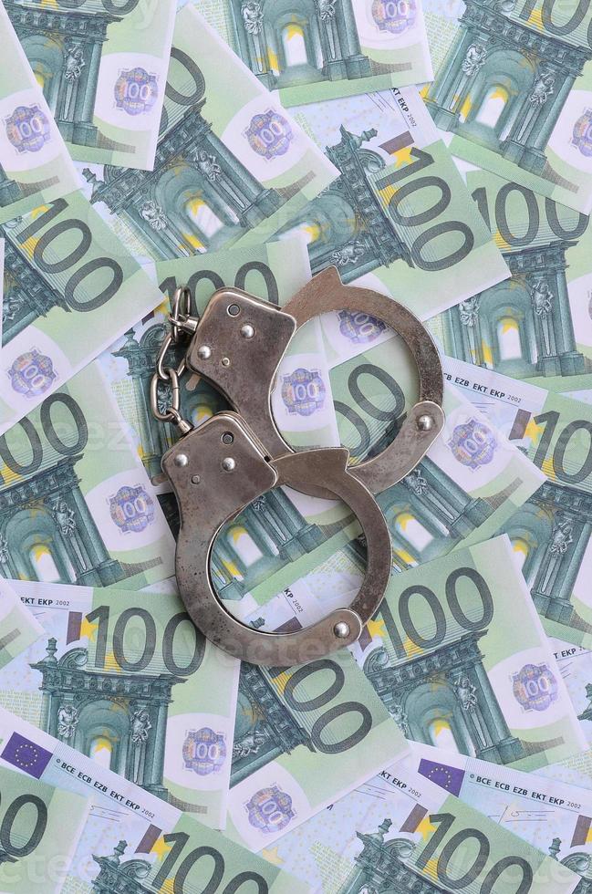 polizia manette bugie su un' impostato di verde monetario denominazioni di 100 euro. un' lotto di i soldi le forme un infinito mucchio foto