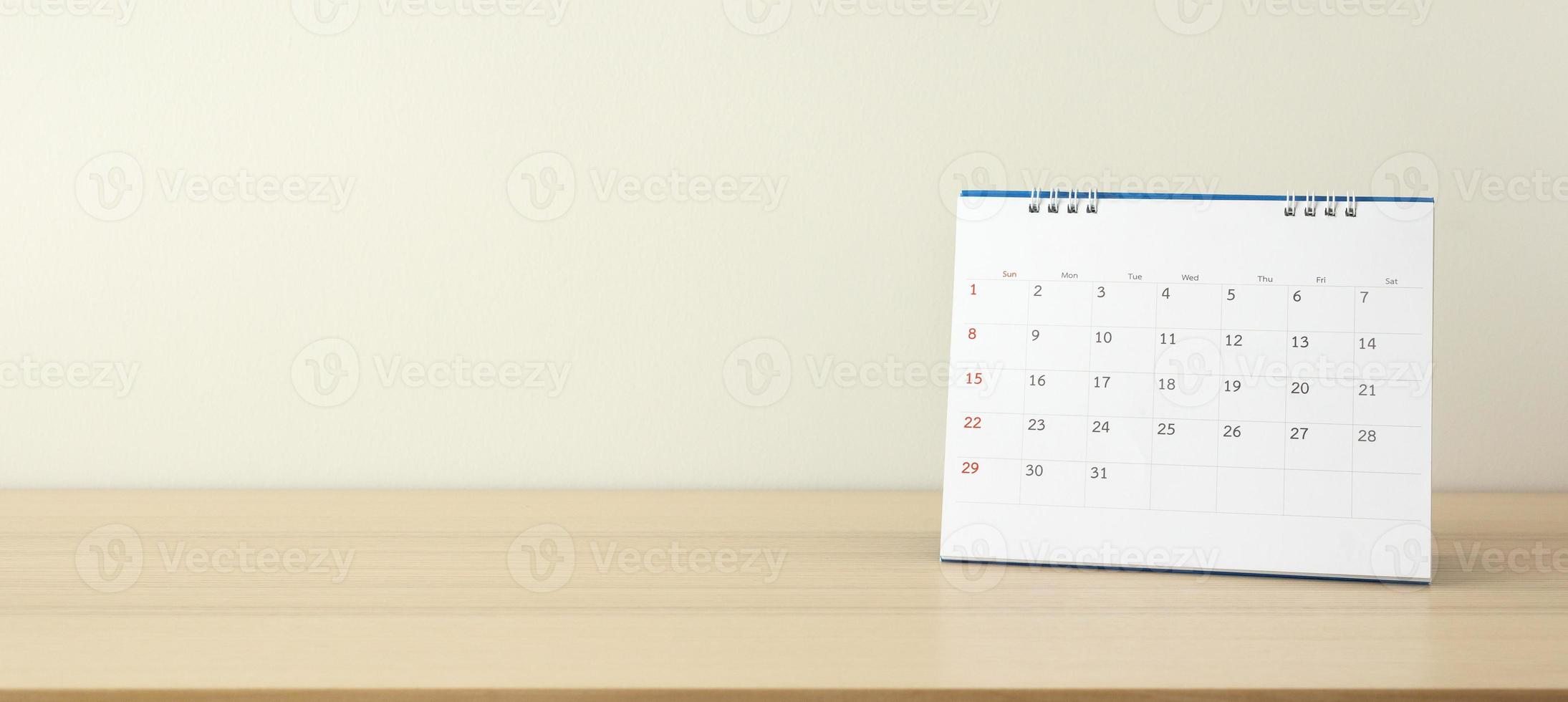 calendario pagina vicino su su legna tavolo con bianca parete sfondo attività commerciale pianificazione appuntamento incontro concetto foto