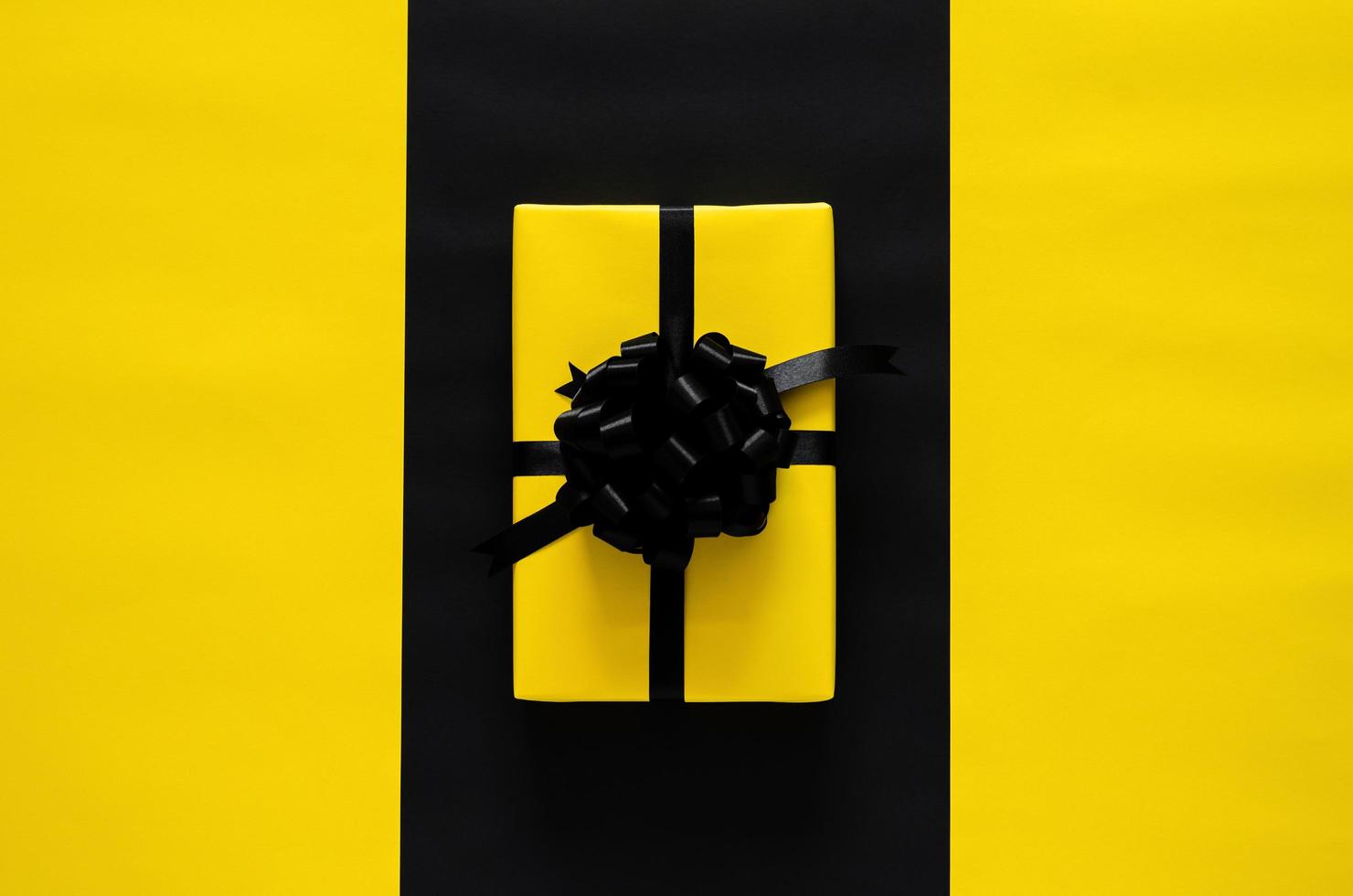 un' giallo regalo scatola con nero nastro mette su nero e giallo sfondo. nero Venerdì e boxe giorno concetto. foto