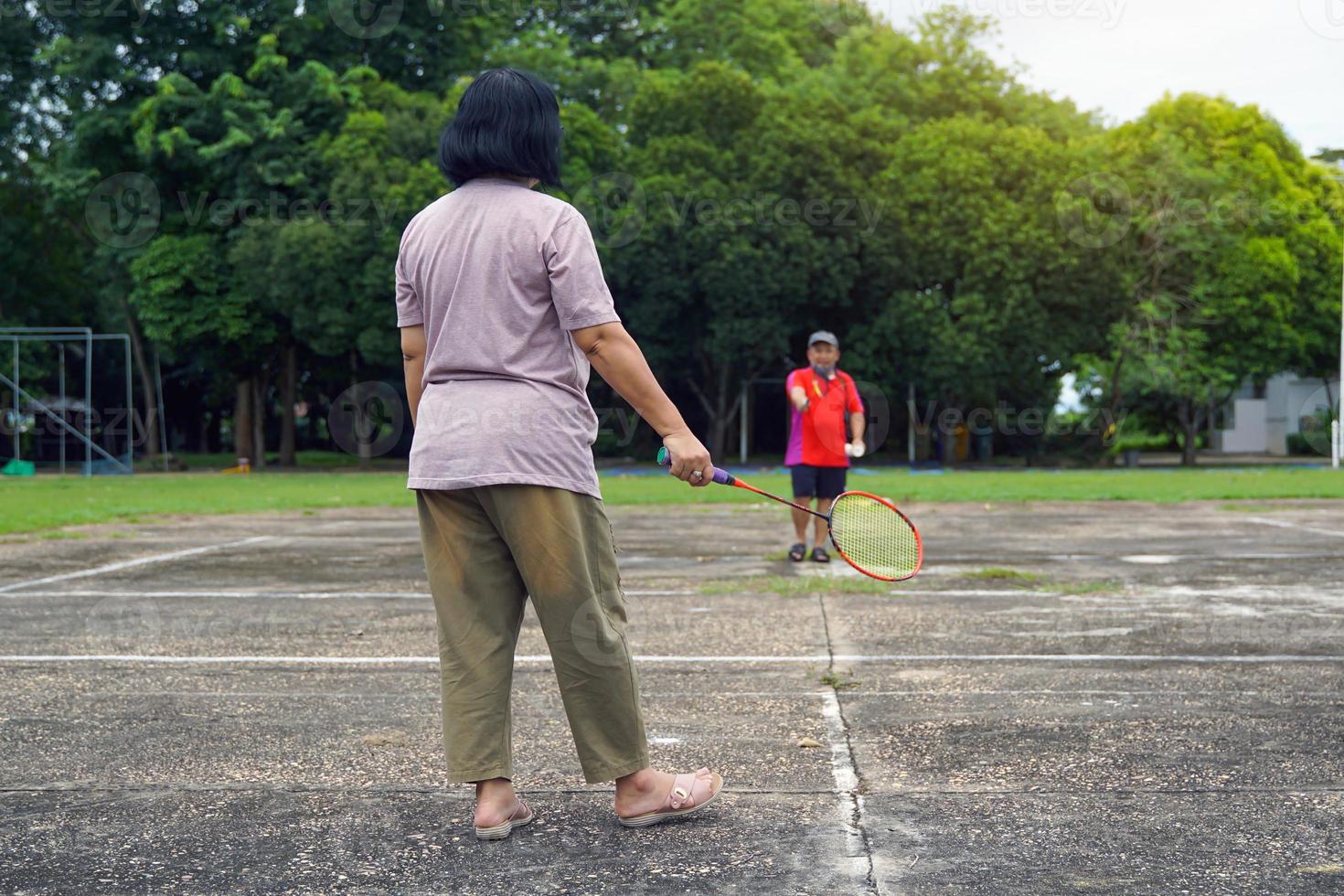 asiatico maschio e femmina badminton Giocatori giocare badminton insieme dopo opera su cortile a opera. concetto, un' tempo libero attività per fare ogni giorno dopo opera, morbido e selettivo messa a fuoco. foto