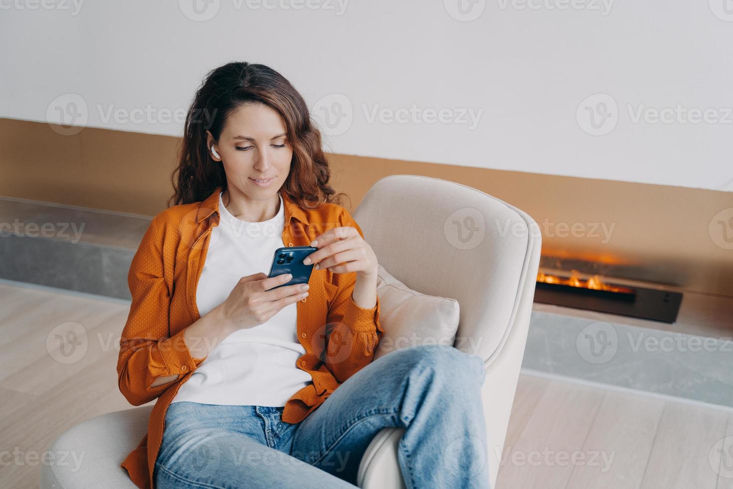 moderno ragazza nel auricolari utilizzando smartphone app, shopping in linea, ascoltando per nuovo Podcast o musica foto