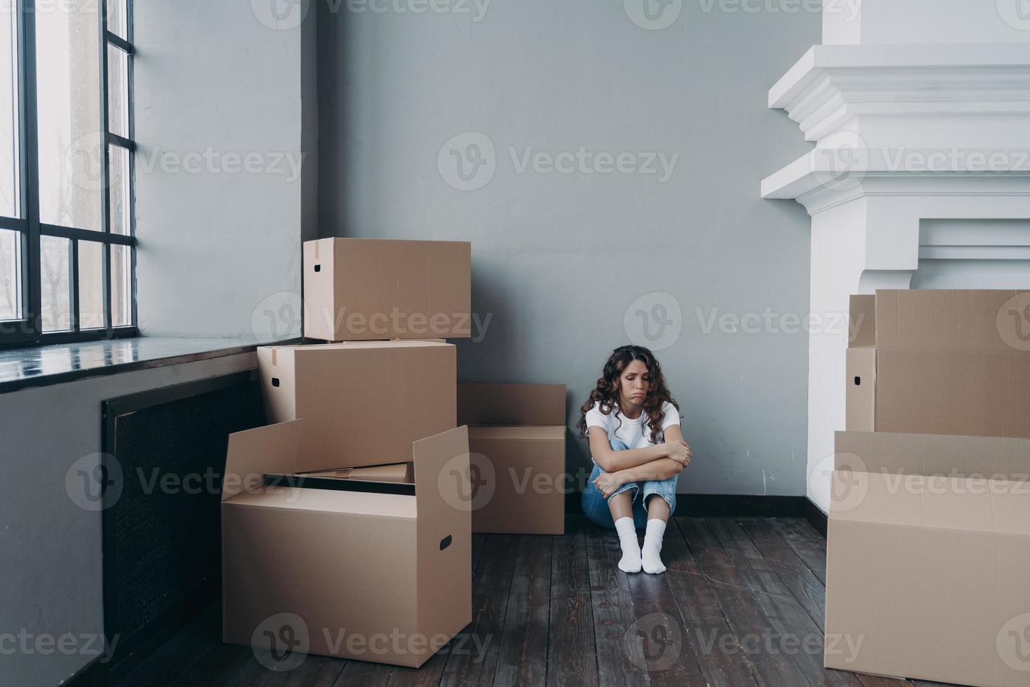 triste donna seduta su il pavimento tra scatola di cartone scatole con cose per in movimento. divorzio, sfratto concetto foto