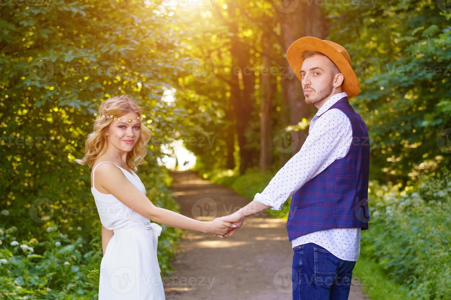 il ragazza detiene mani con un' uomo su il sfondo di il sentiero nel il foresta. foto