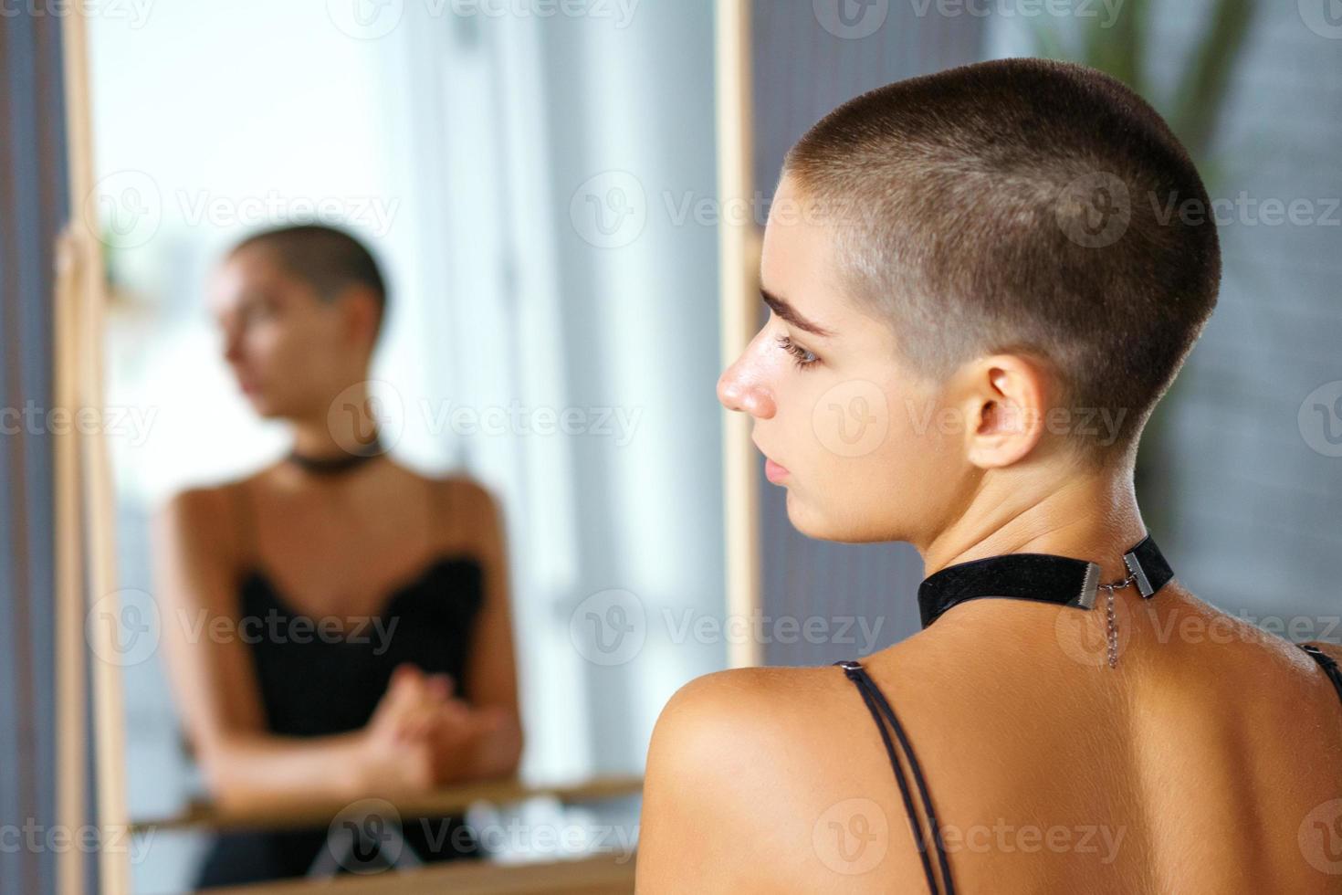 ragazza con corto capelli sembra animatamente per il lato, il riflessione nel il specchio foto