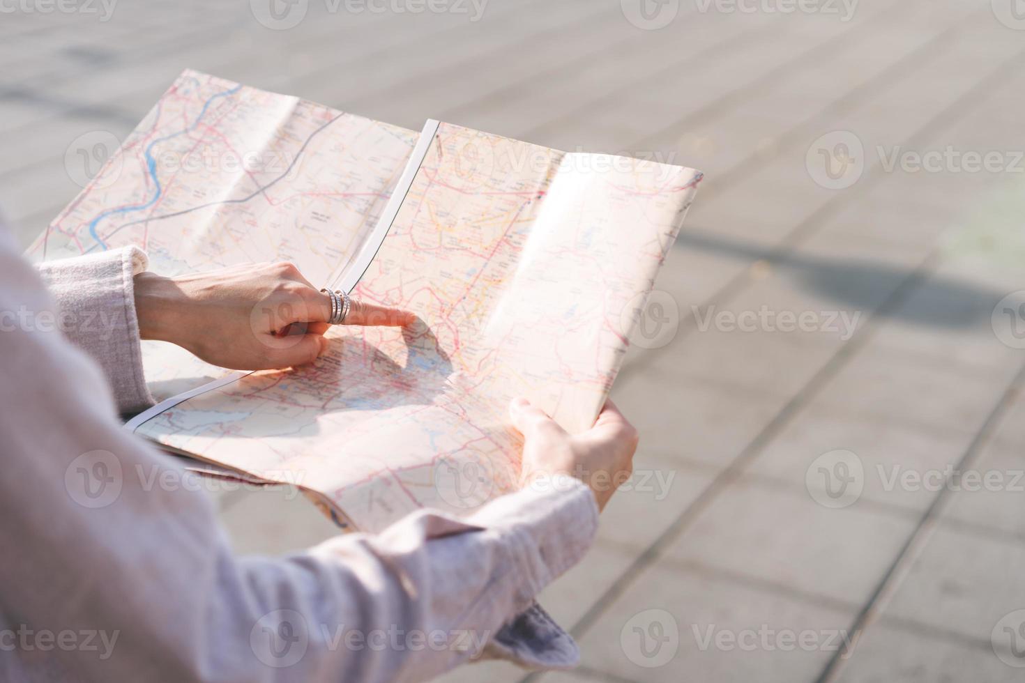 asiatico donna mano punto su carta geografica durante in viaggio a all'aperto su giorno. foto