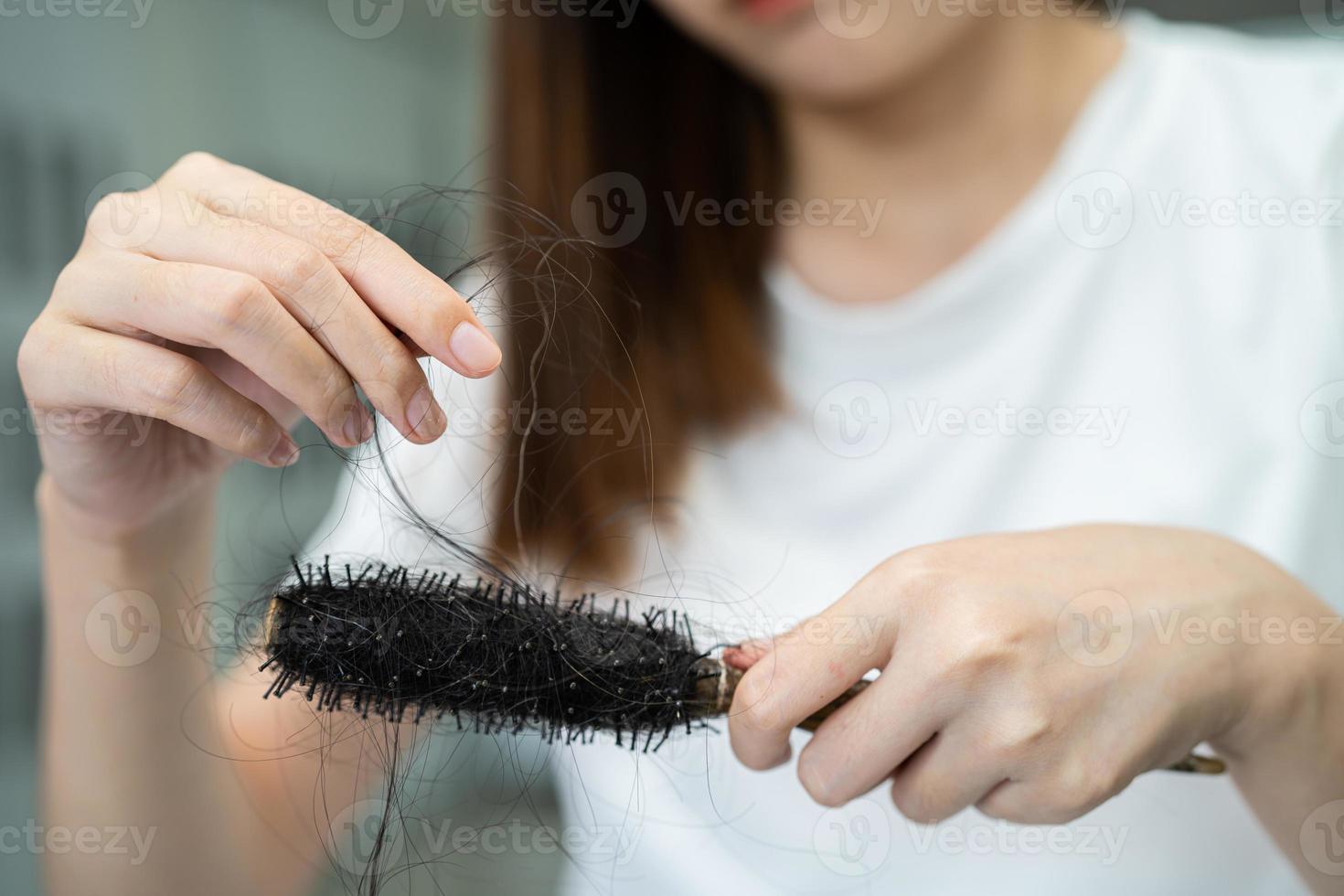 la donna asiatica ha problemi con la caduta dei capelli lunghi attaccata alla spazzola del pettine. foto