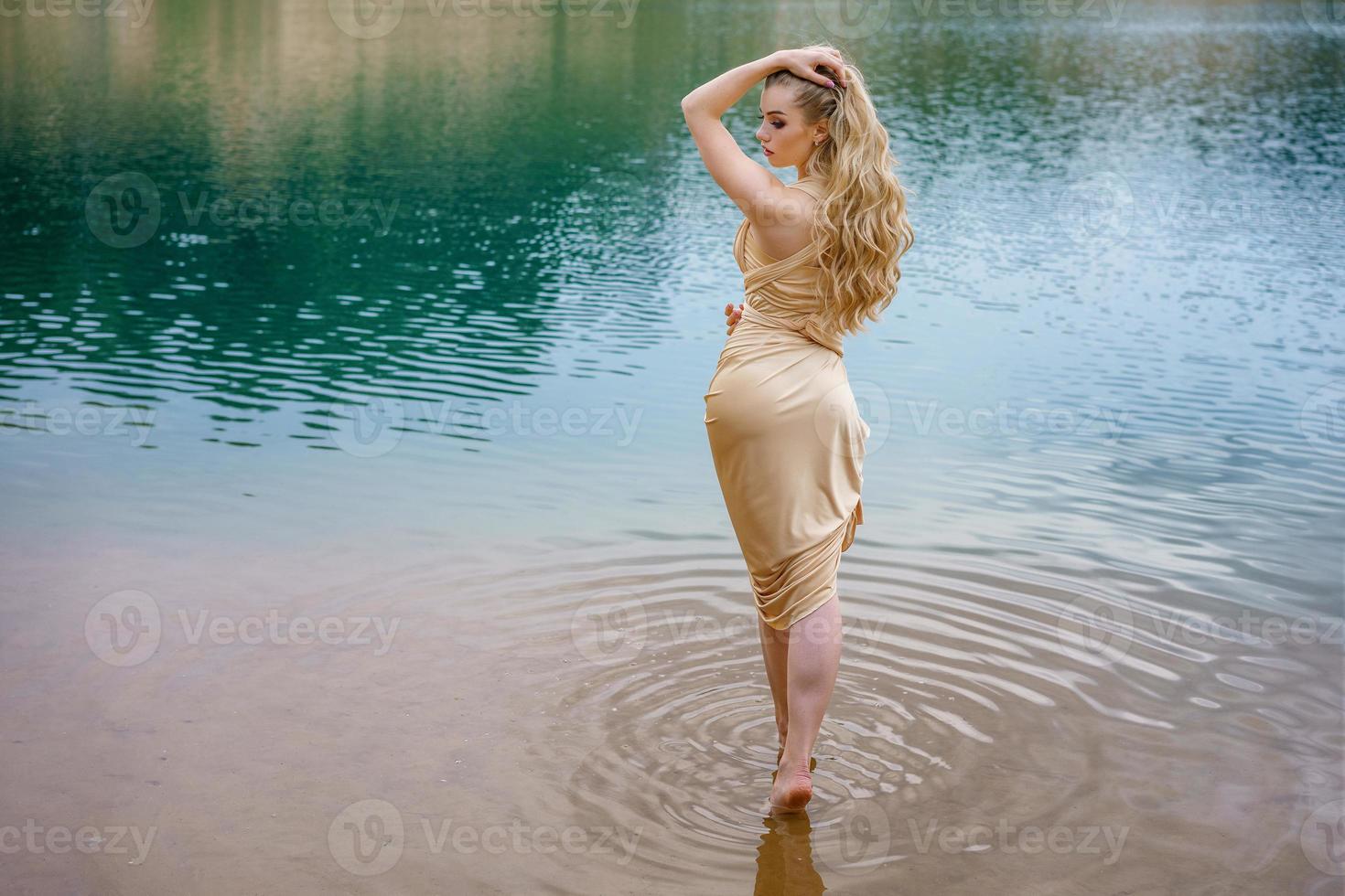 bellissimo snello ragazza con lungo capelli in posa in piedi nel il acqua foto