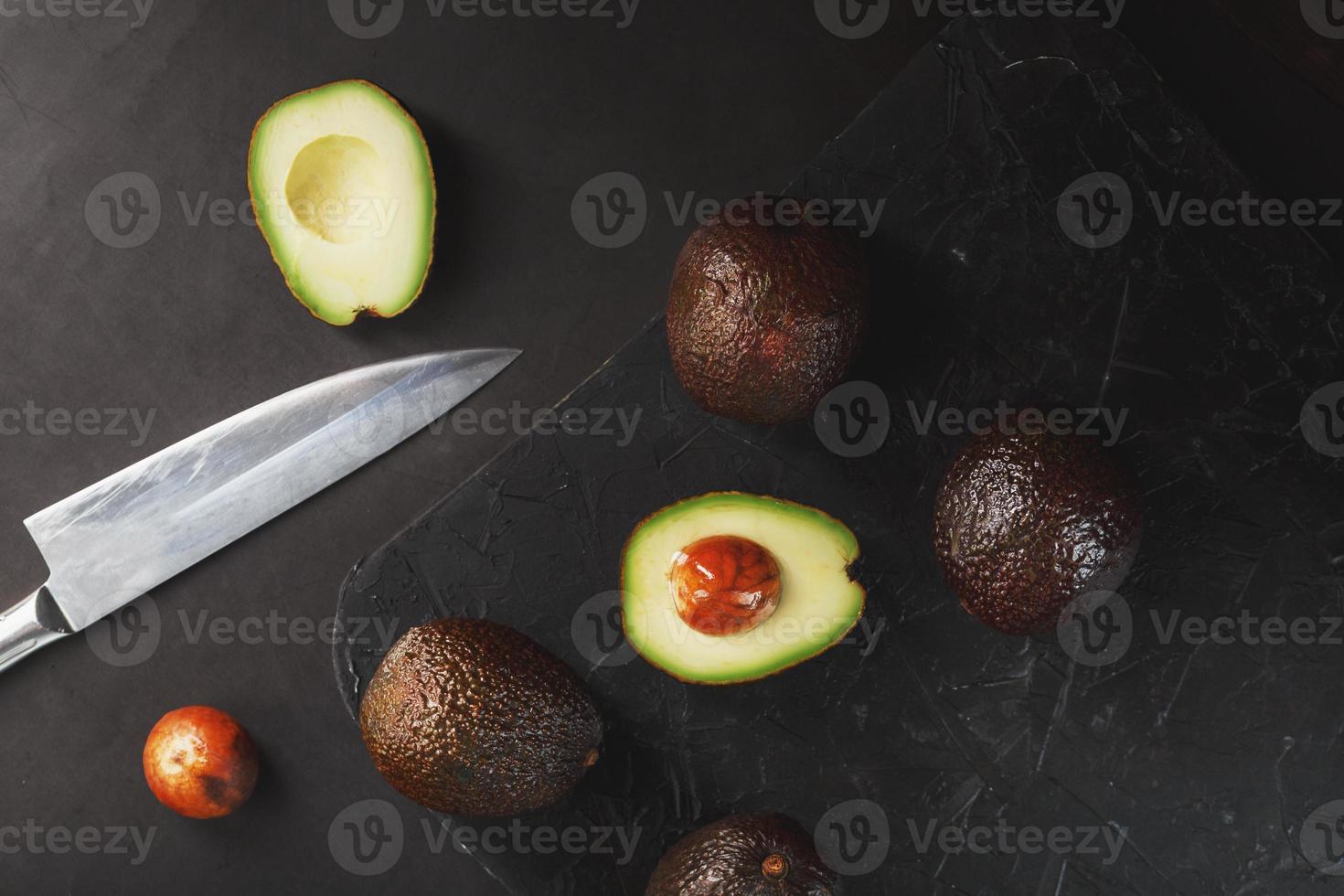 affettato e totale biologico avocado seccatura con un' coltello su un' nero sfondo. foto