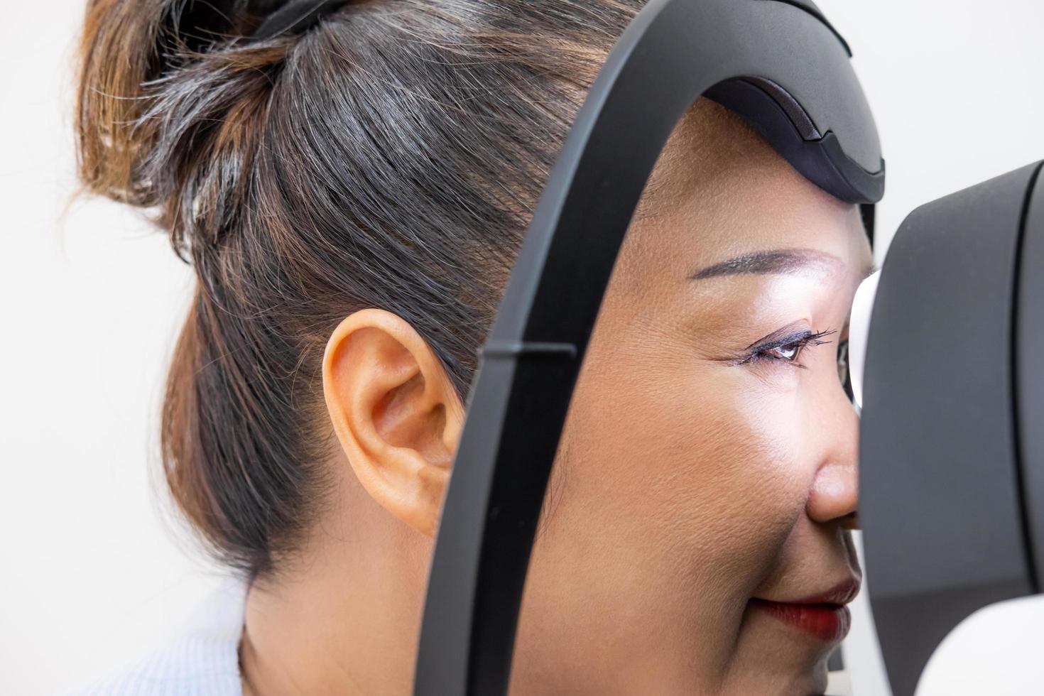 Sambuco asiatico donne a il optometria attrezzatura. mentre optometrista utilizzando soggettivo rifrazione per esaminare occhio visivo sistema di Sambuco paziente donne con professionale macchina prima fatto occhiali. foto