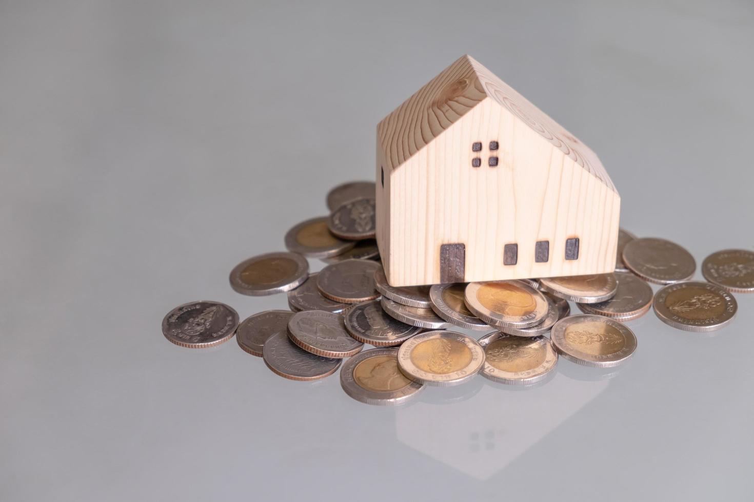 selettivo messa a fuoco a di legno Casa finto su quello mettere su il superiore di crescita i soldi monete pila su il bicchiere tavolo con sfocato sfondo. ricchezza e Salvataggio per casa Proprietà e finanziario concetto. foto