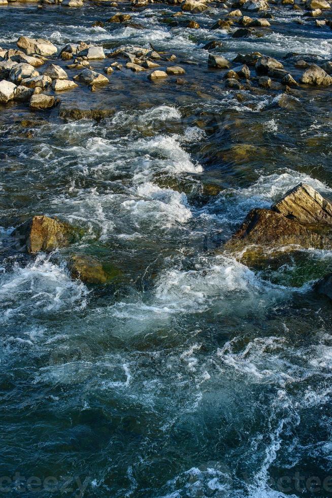 fluire, per un' tempestoso fiume tra il rocce nel il autunno parco su un' caldo giorno foto