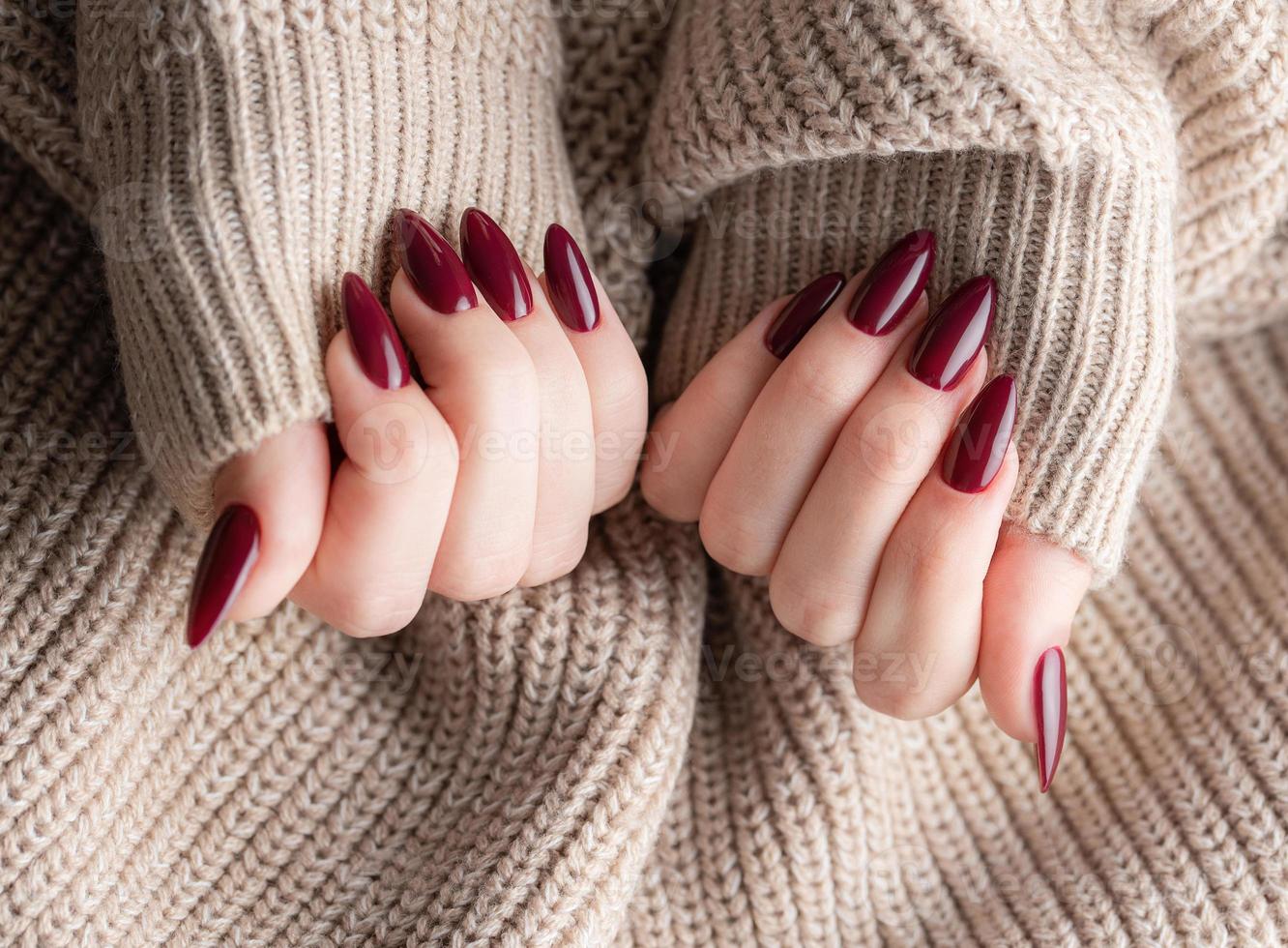 mani di un' giovane donna con buio rosso manicure su Chiodi foto