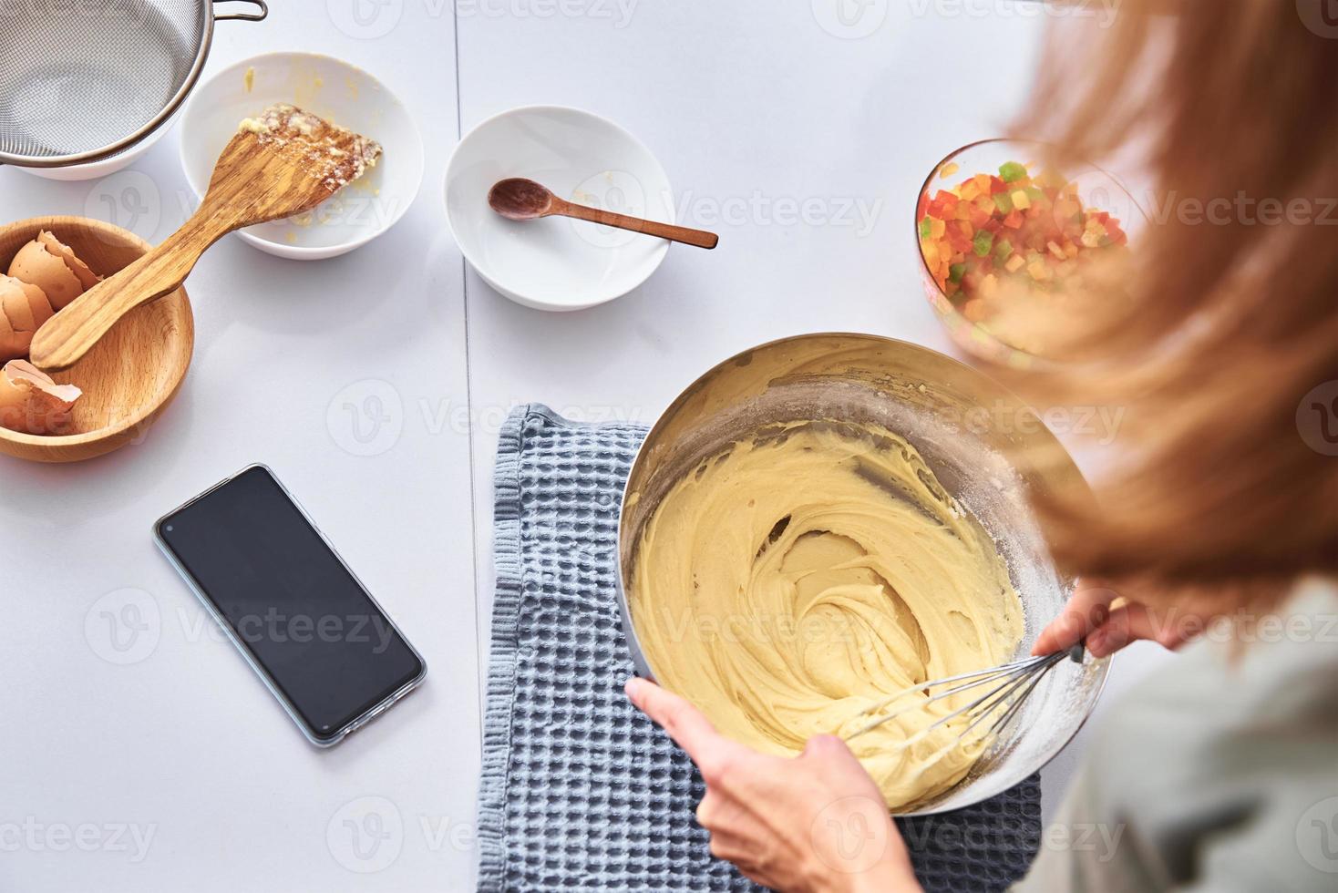 donna nel cucina cucinando un' torta. mani battere il Impasto con miscelatore foto