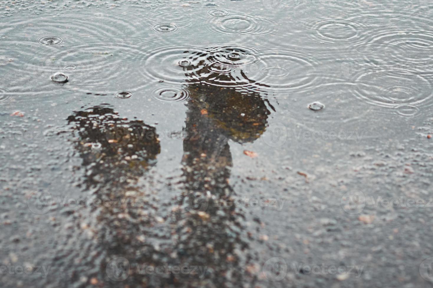 riflessione di Due stivali da pioggia nel un' pozzanghera a piovoso giorno foto