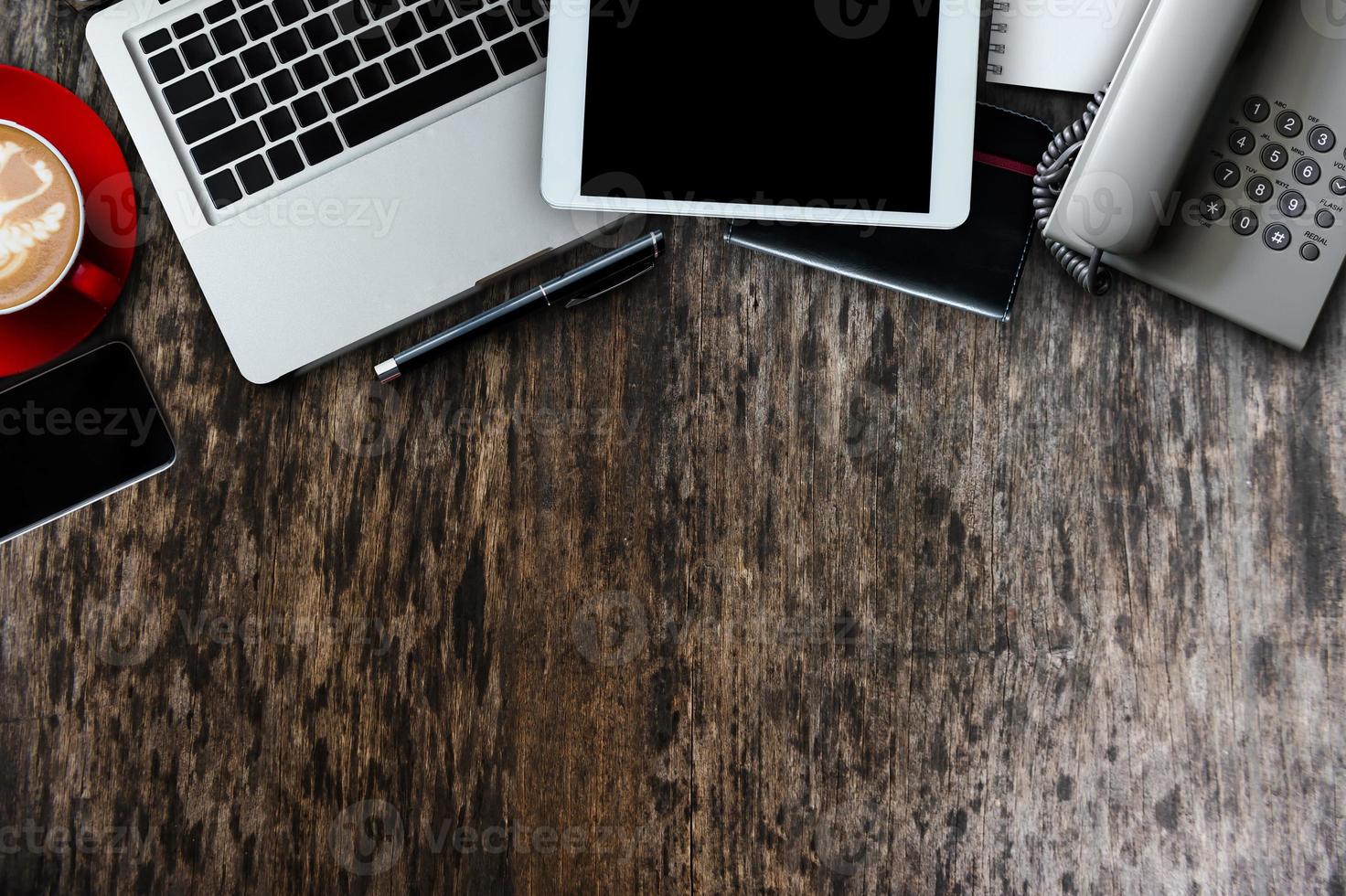 roba da ufficio con tablet, laptop, smartphone e blocco note con tazza di caffè e documenti vista dall'alto. foto