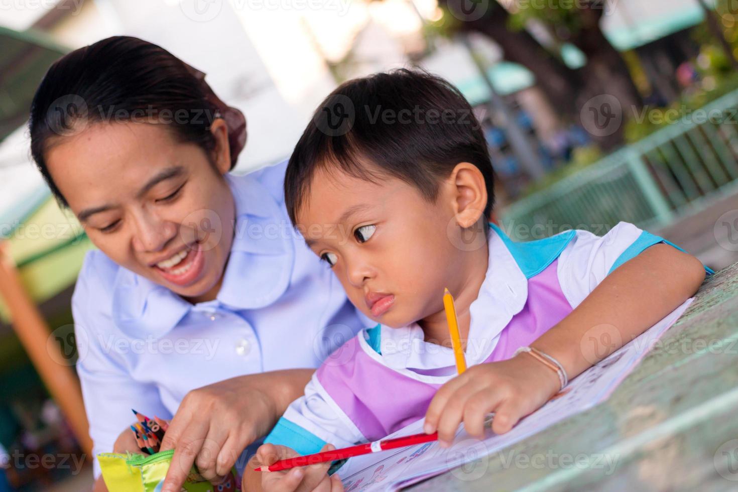 un' madre nel un' assistenza infermieristica uniforme è insegnamento sua figlio compiti a casa. foto