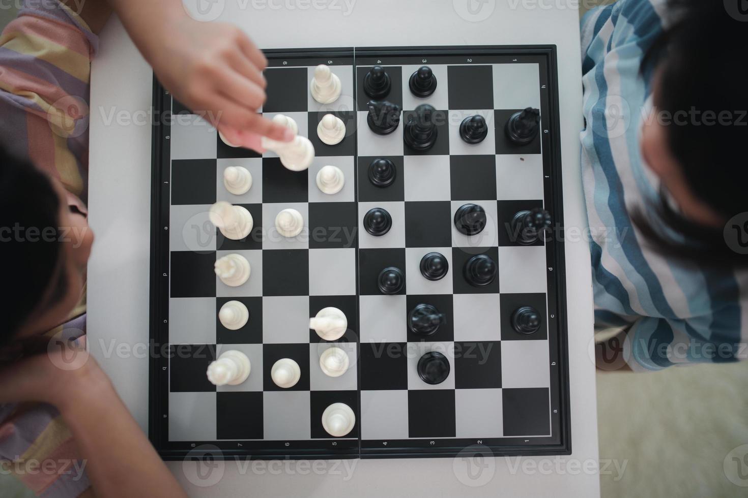 poco fratello ragazza giocando scacchi a casa. foto
