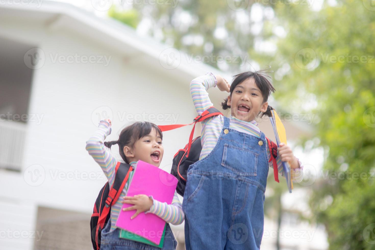 bambini con zaini salto nel il parco vicino scuola. allievi con libri e zaini all'aperto foto