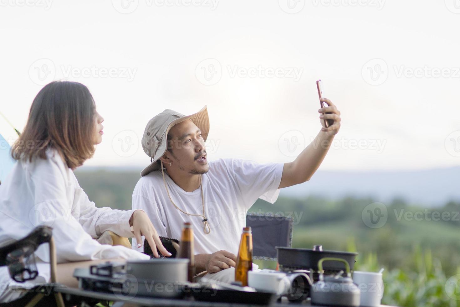 contento asiatico coppia giocare chitarra e cantare godere campeggio e potabile birra. foto