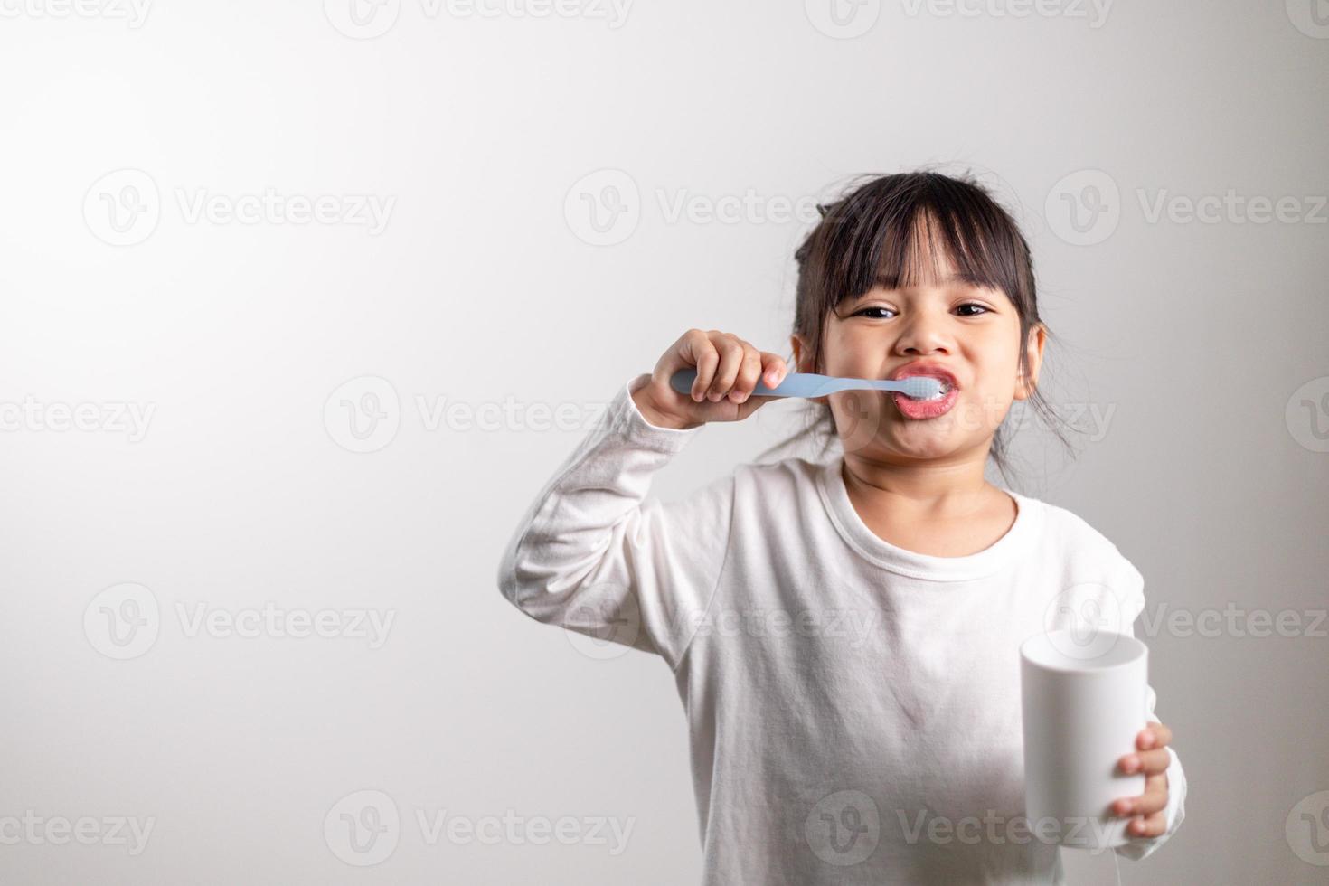 poco carino bambino ragazza spazzolatura sua denti su bianca sfondo. spazio per testo. salutare denti. foto