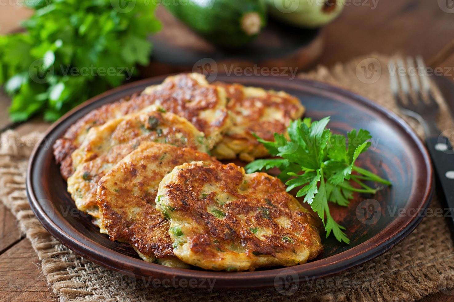 frittelle di zucchine con prezzemolo su un tavolo di legno foto