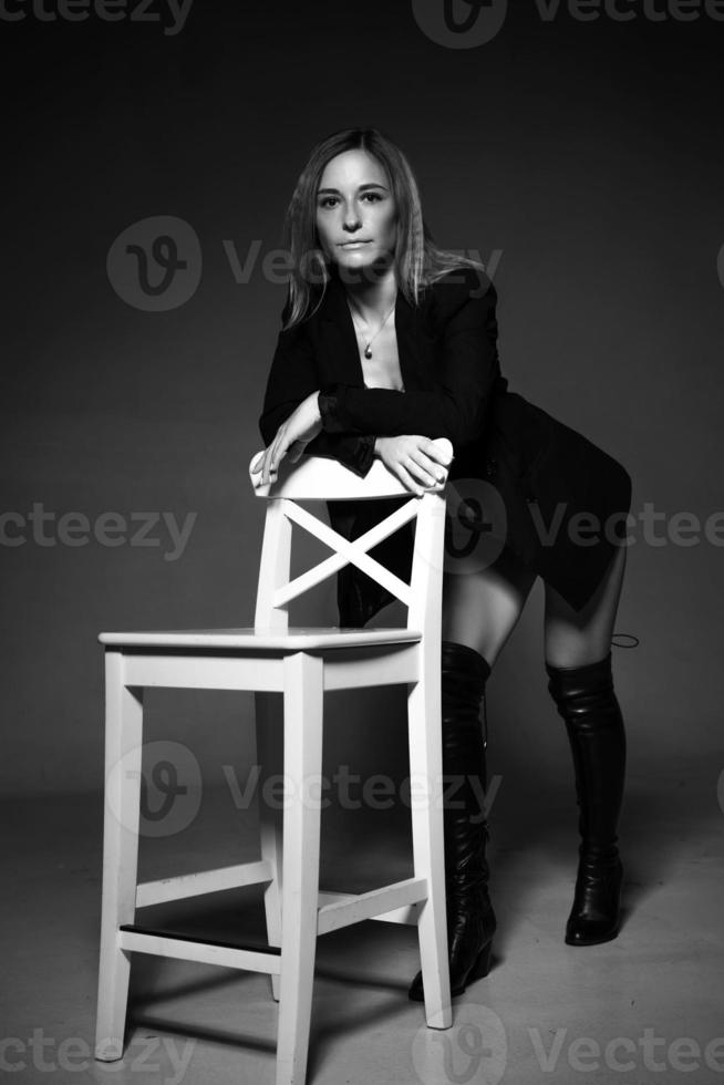 donna in posa seduta su un' sedia nel giacca e biancheria intima, nero e bianca foto