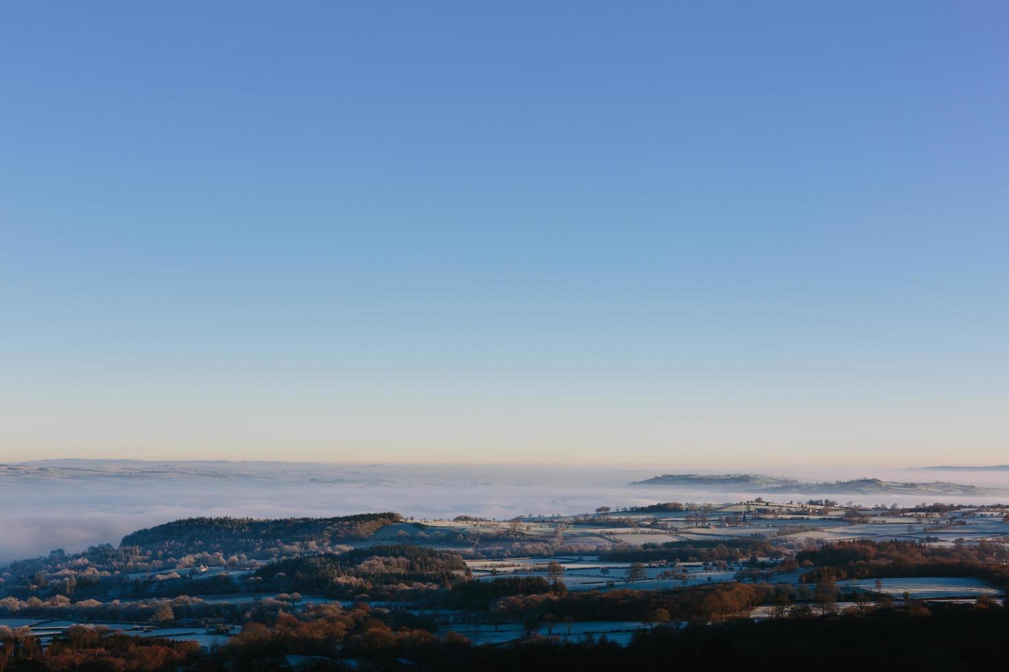 vista aerea di montagne nebbiose e cielo blu foto