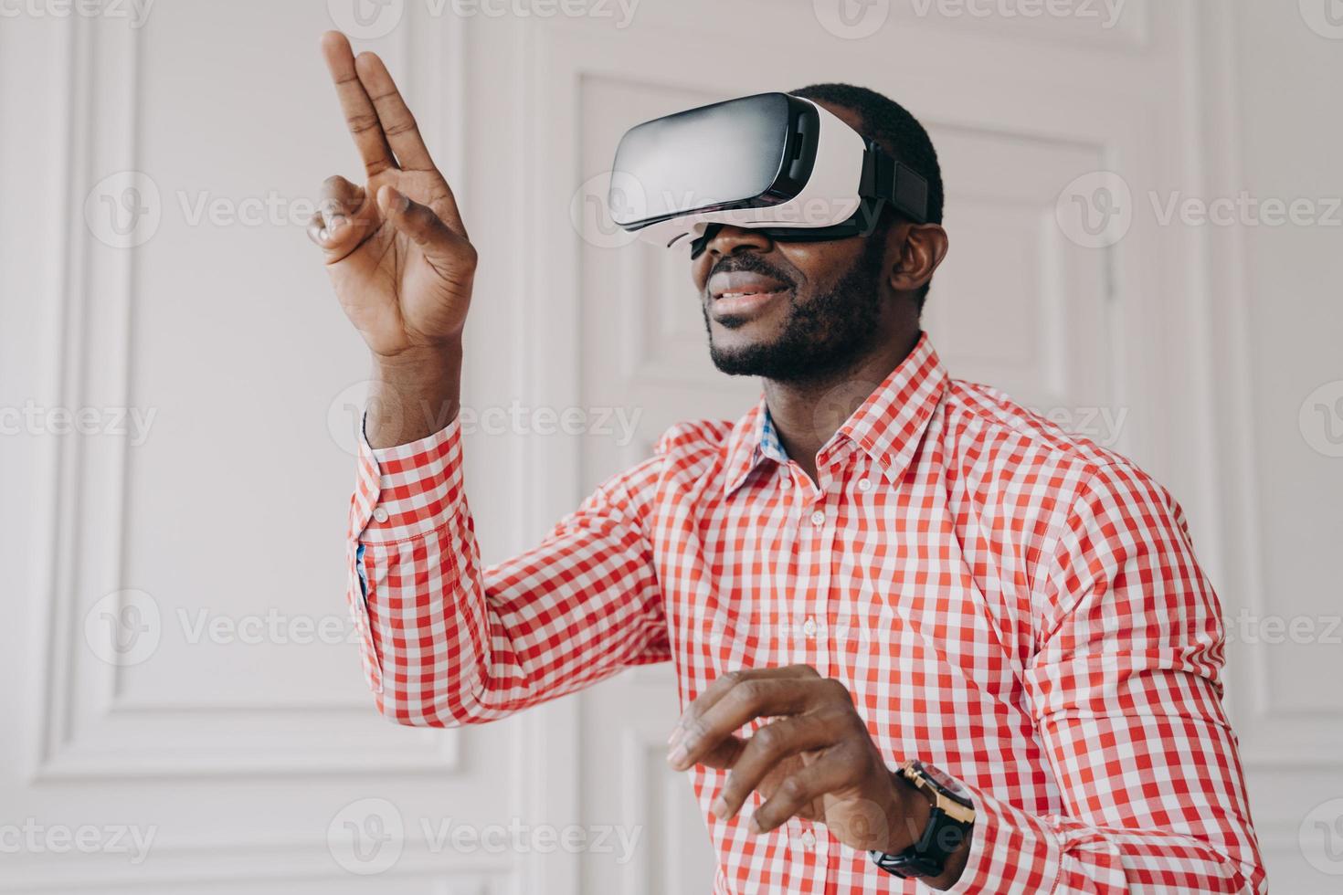 impressionato ragazzo di etnia africana in occhiali vr headset godendo la realtà virtuale online al lavoro foto