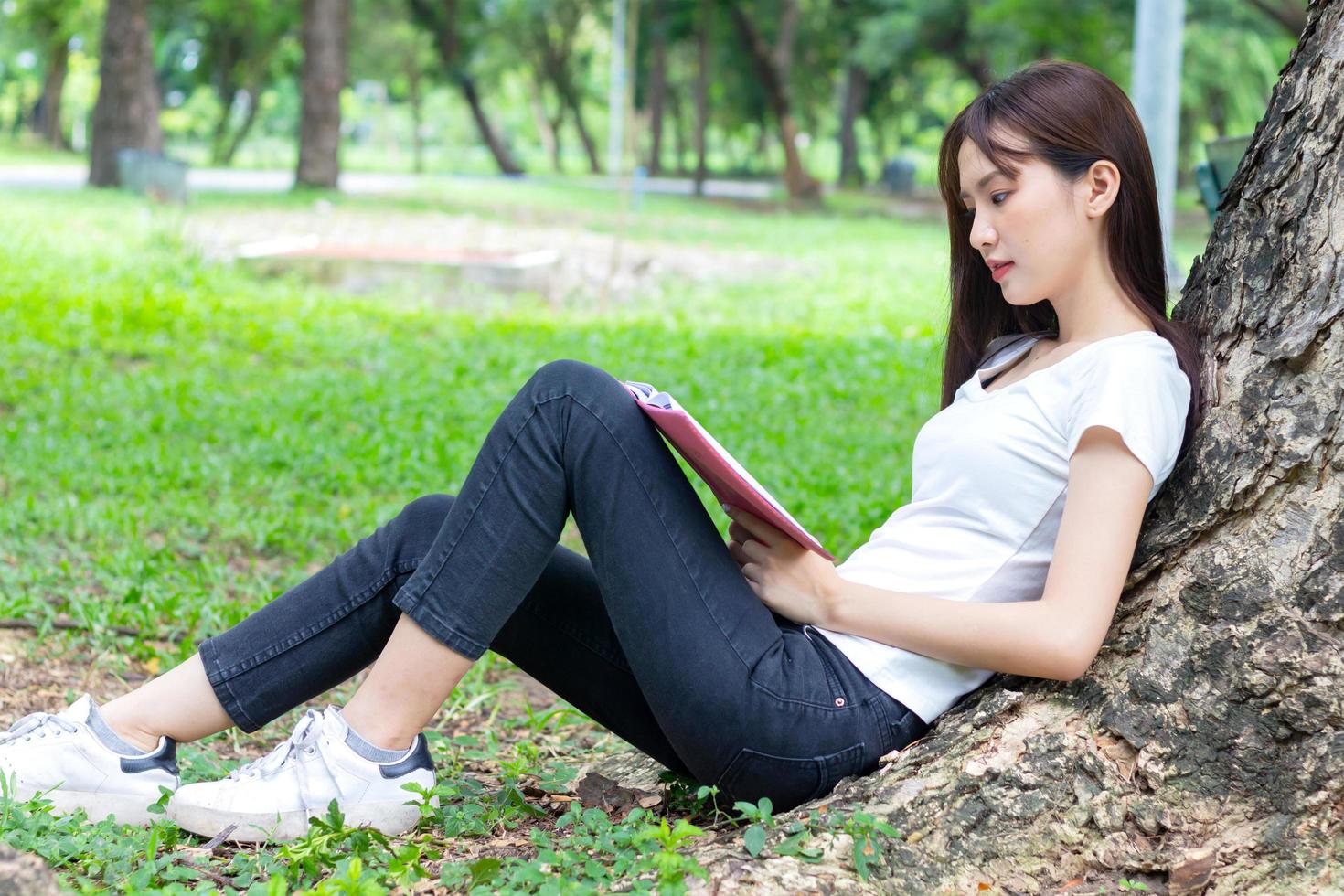 donna asiatica che legge un libro nel parco foto