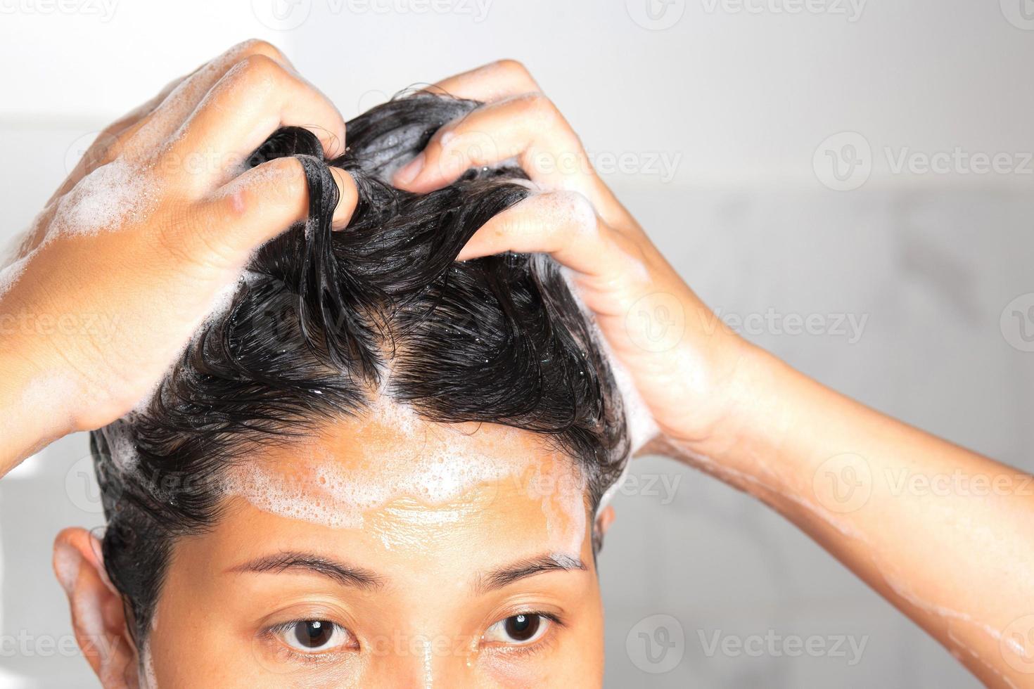 asiatico donna lavaggio sua capelli mentre assunzione un' doccia. foto