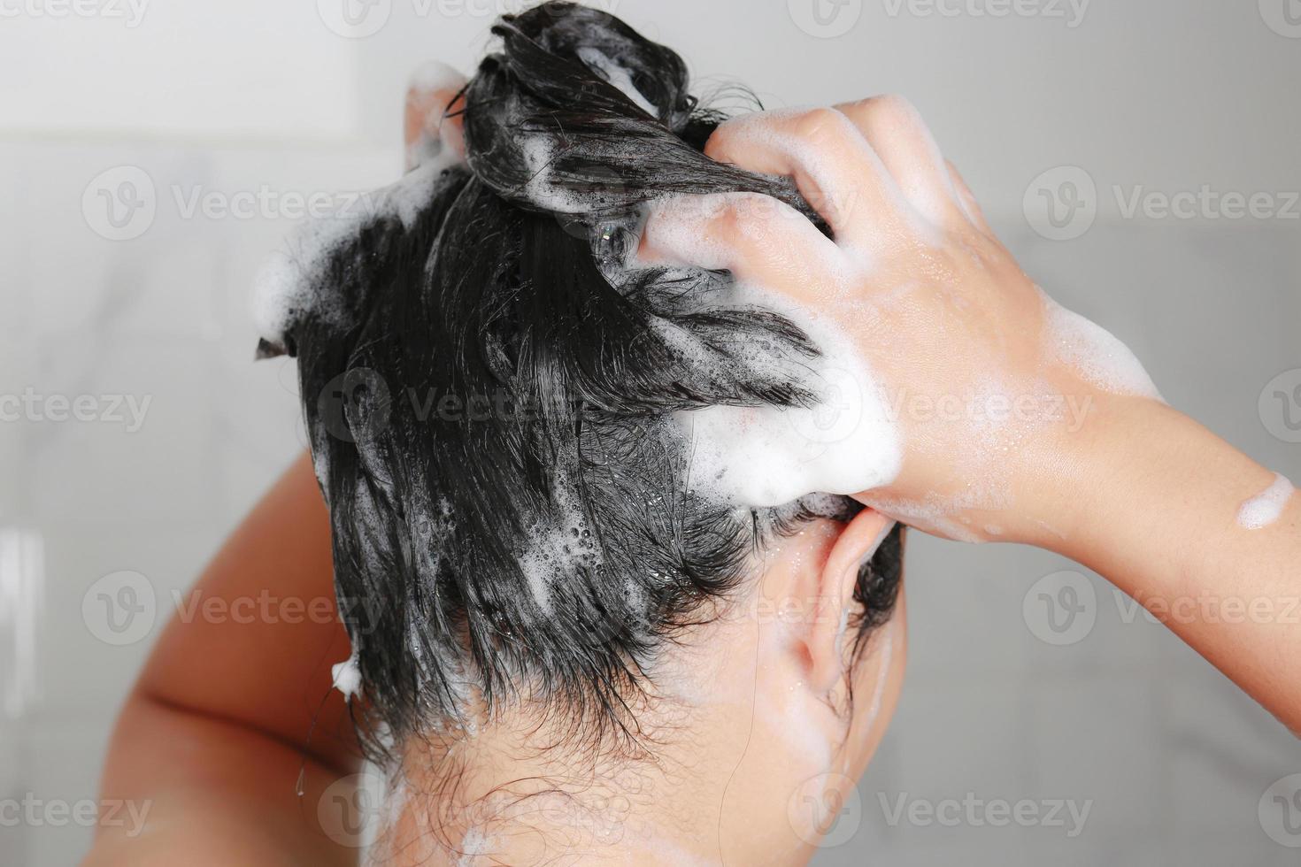 asiatico donna lavaggio sua capelli mentre assunzione un' doccia. foto