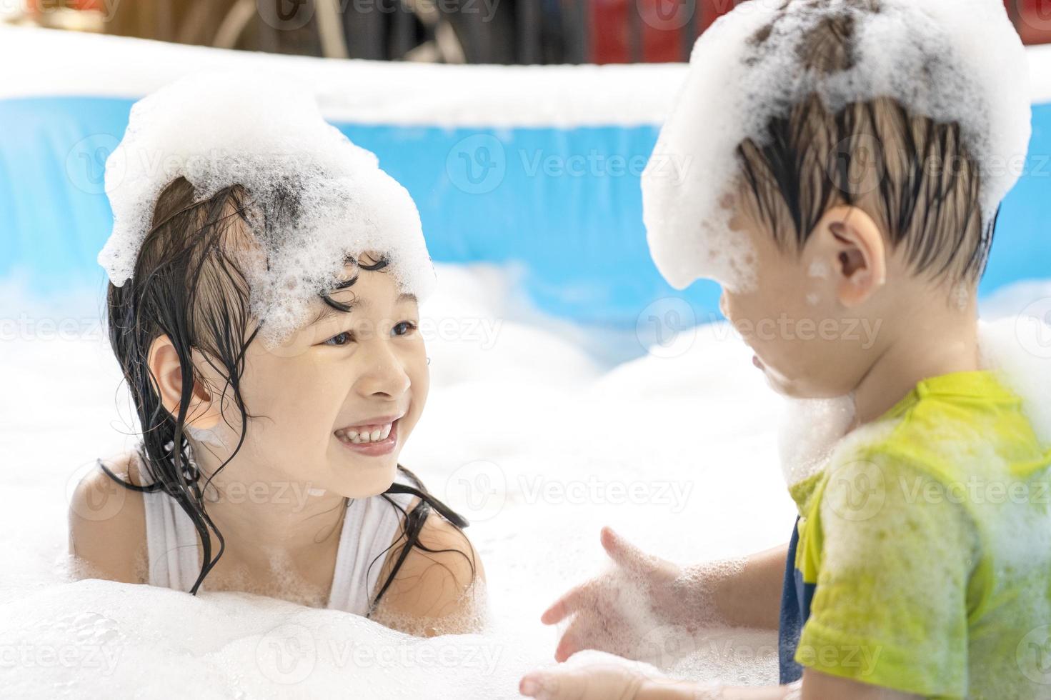 carino asiatico fratelli avendo divertimento nel il nuoto piscina. sorella e fratello giocando con bolle e nuoto nel il estate vacanza piscina. contento famiglia vacanza concetto foto