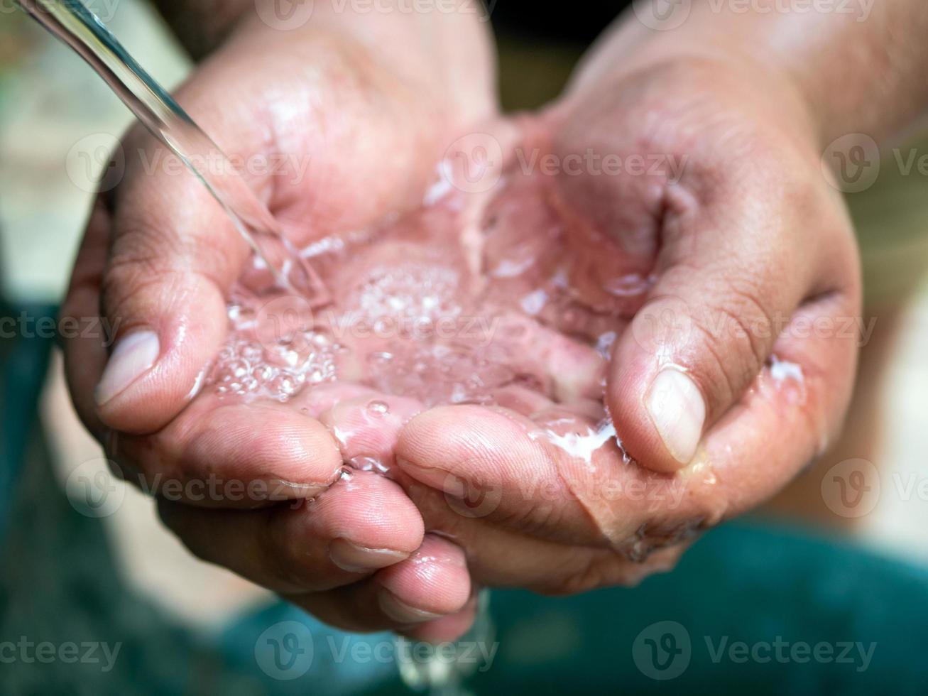 chiaro acqua fluente a partire dal un' potabile Fontana in a coppa mans palme. vivificante umidità su un' caldo giorno. foto