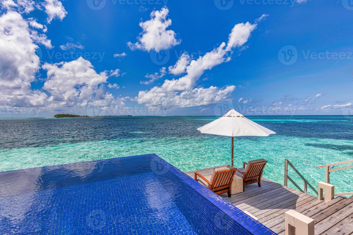 Maldive lusso spiaggia ricorrere. infinito nuoto piscina, spiaggia sedie o lettini sotto ombrelli nel al di sopra di acqua villa. blu cielo, sorprendente laguna. estate vacanza, viaggio vacanza. all'aperto turismo paesaggio foto