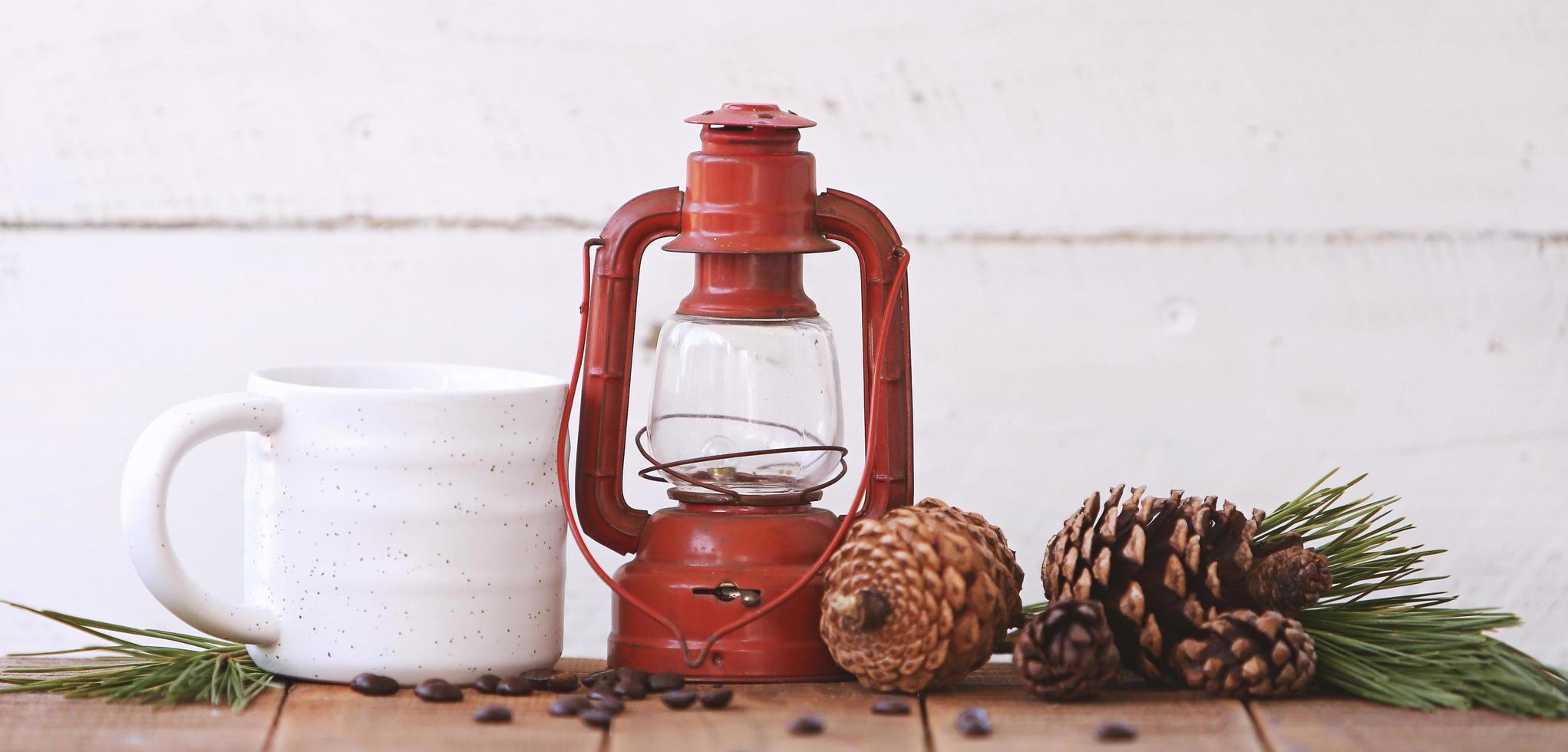 lanterna e una tazza di caffè con pigne foto