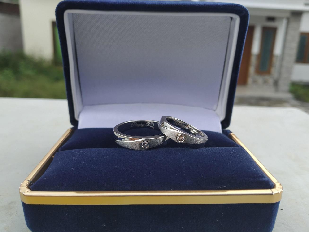 un' paio di nozze anelli e Fidanzamento anelli con argento Materiale posto su un' blu squillare scatola e sfocato sfondo foto