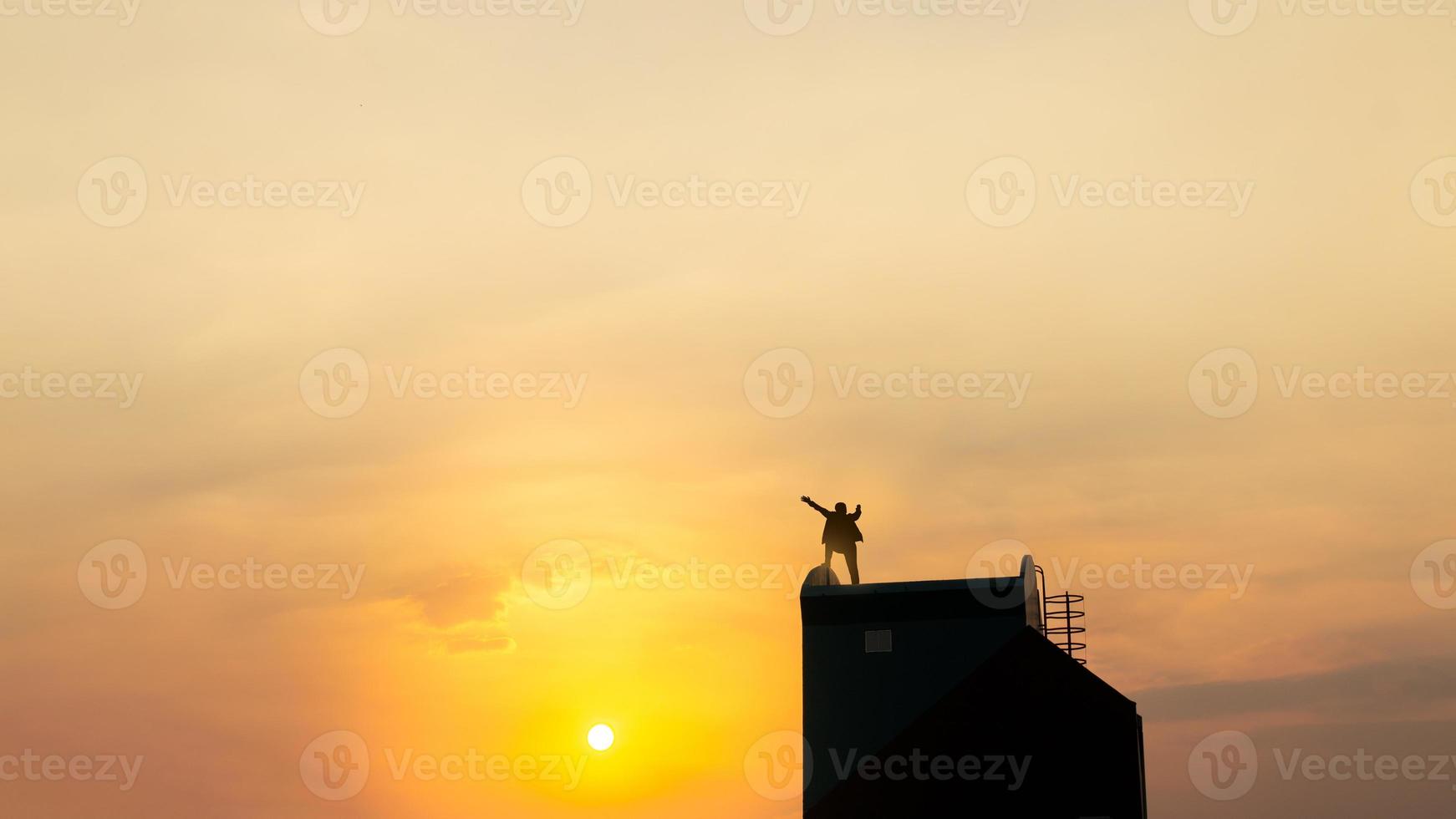 silhouette di uomo su rofftop al di sopra di cielo e sole leggero sfondo, affari, successo, comando, realizzazione e persone concetto foto