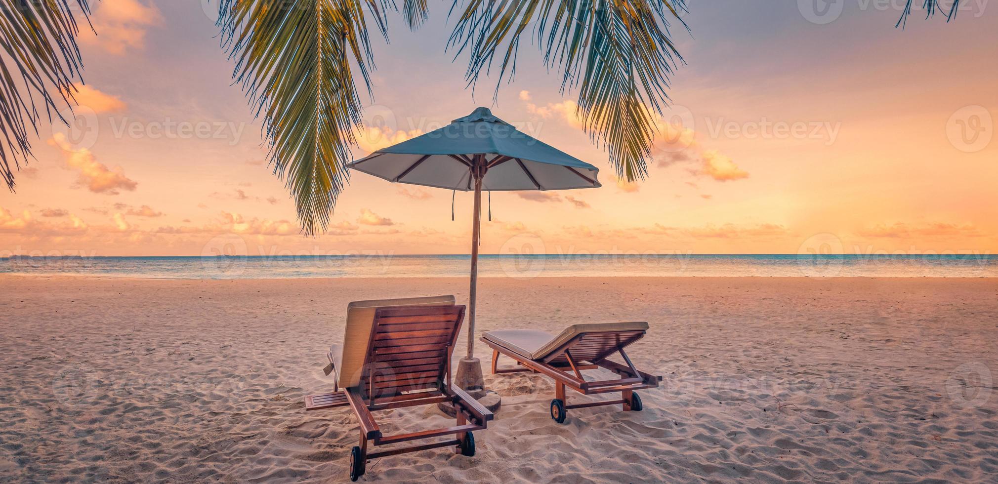 bellissimo tropicale tramonto scenario, coppia sedie, lettini, ombrello sotto palma albero. avvicinamento mare sabbia cielo orizzonte, colorato crepuscolo nuvole, rilassare tranquillo vacanza paesaggio. estate vacanza, idilliaco foto