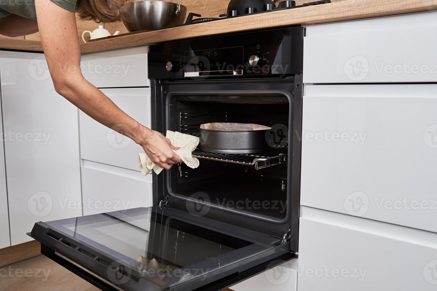 donna cucinando torta nel elettrico forno foto