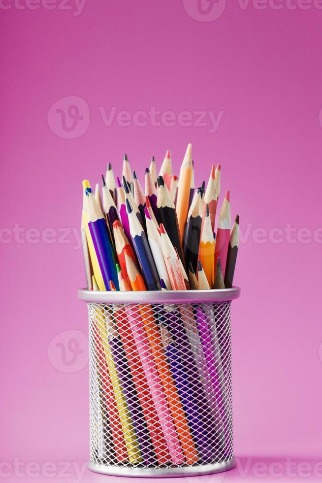 matite di diverso colori nel un' bicchiere su un' rosa sfondo. foto